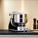 Ankarsrum Assistent Original Stand Mixer in black (akm-6230-b) base package includes a stainless bowl, dough roller, dough knife, spatula, dough hook, proving lid, 3.5L Tritan plastic whisking bowl, balloon whisks, and shortcrust dough hooks for versatile baking and mixing.