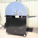 Back view of the Pyro Kitchen Caldo V2 Hybrid Pizza Oven with drip tray, gas connection, and stainless steel burner cover for durability when using wood.