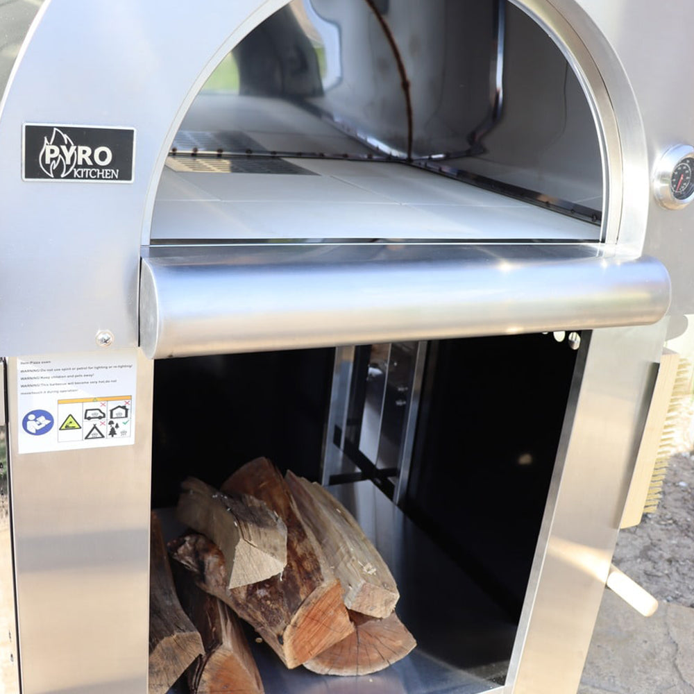 Close-up front view of the Pyro Kitchen Vera V2 Wood Fired Pizza Oven with logs stored neatly under the oven in the protected storage area.